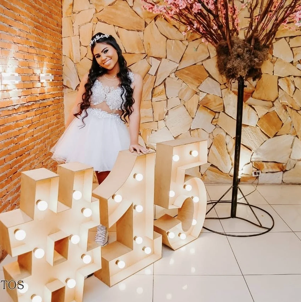 Debutante ao lado do letreiro iluminado 15 em festa no Buffet Dream Hall