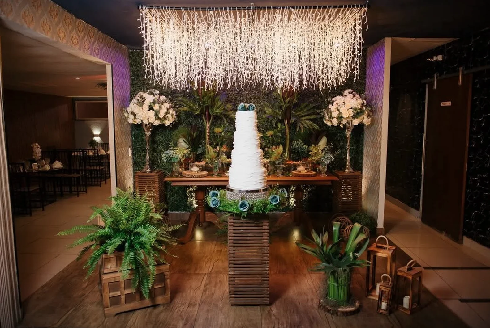 Mesa do bolo com decoração verde e luzes em casamento no Buffet Dream Hall